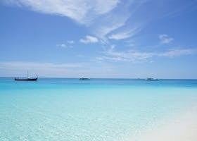 Peaceful beach scene with crystal clear waters and a deep blue sky, ideal for travel inspiration.